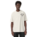A model wearing an oversized off-white t-shirt with a black graphic logo on the left chest, paired with dark jeans, against a plain white background.