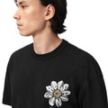 A close-up side profile of a person wearing a black crewneck t-shirt with a large white and gray flower graphic on the front, set against a plain white background.