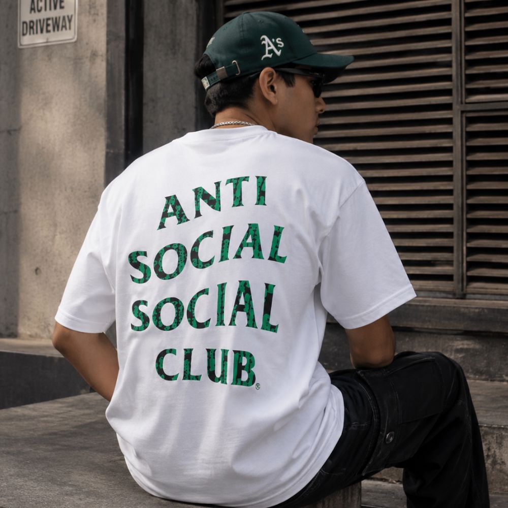 A white short-sleeve crewneck t-shirt with the text 'ANTI SOCIAL SOCIAL CLUB' printed in green on the left chest, shown against a plain white background.