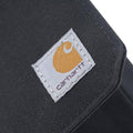 Close-up of a black woven fabric product featuring a stitched square Carhartt logo patch on the side.