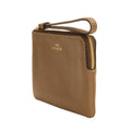 A Coach pebbled leather wristlet pouch in a warm tan-brown color, featuring a gold-tone zipper and a gold-embossed logo on the front, set against a plain white background.