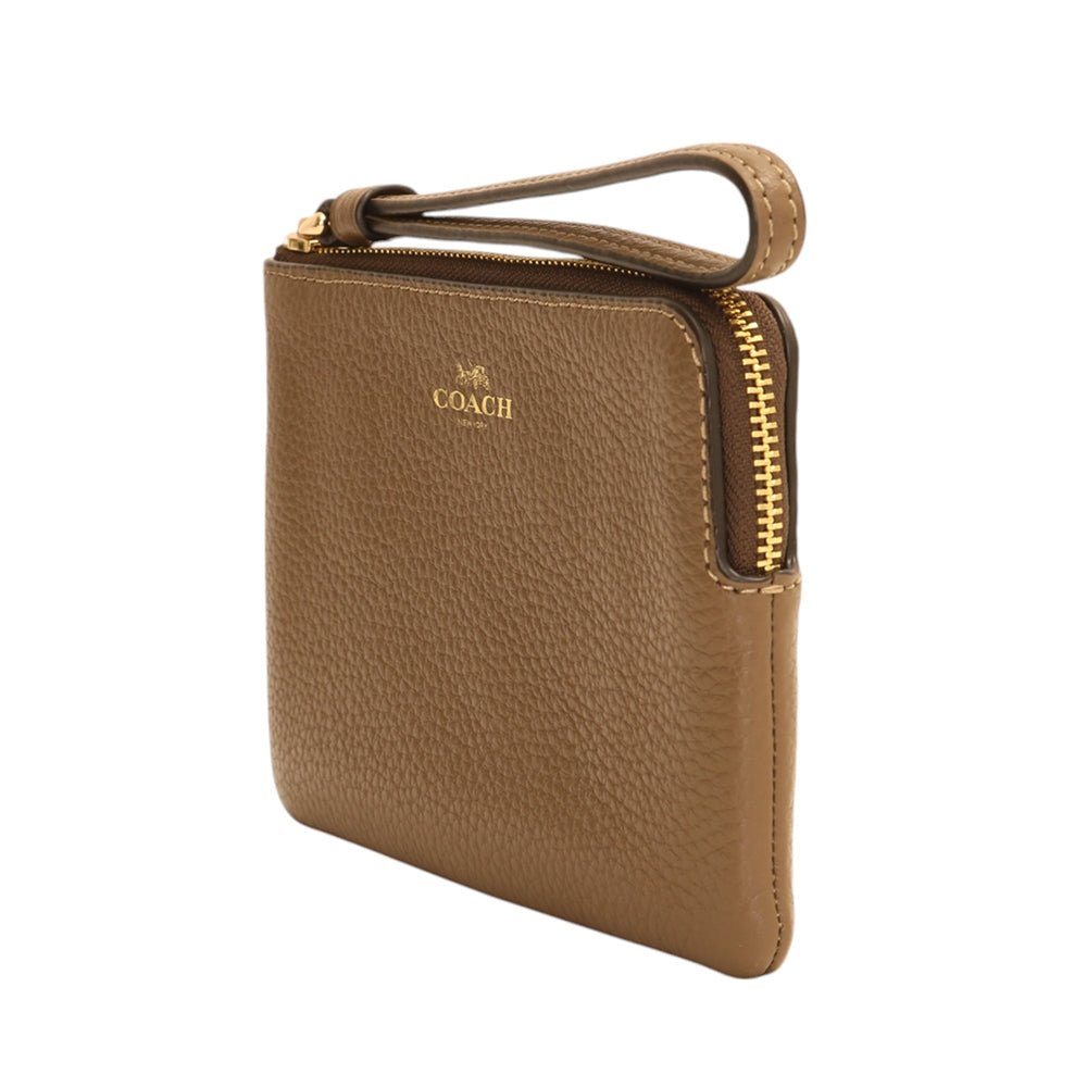 A Coach pebbled leather wristlet pouch in a warm tan-brown color, featuring a gold-tone zipper and a gold-embossed logo on the front, set against a plain white background.