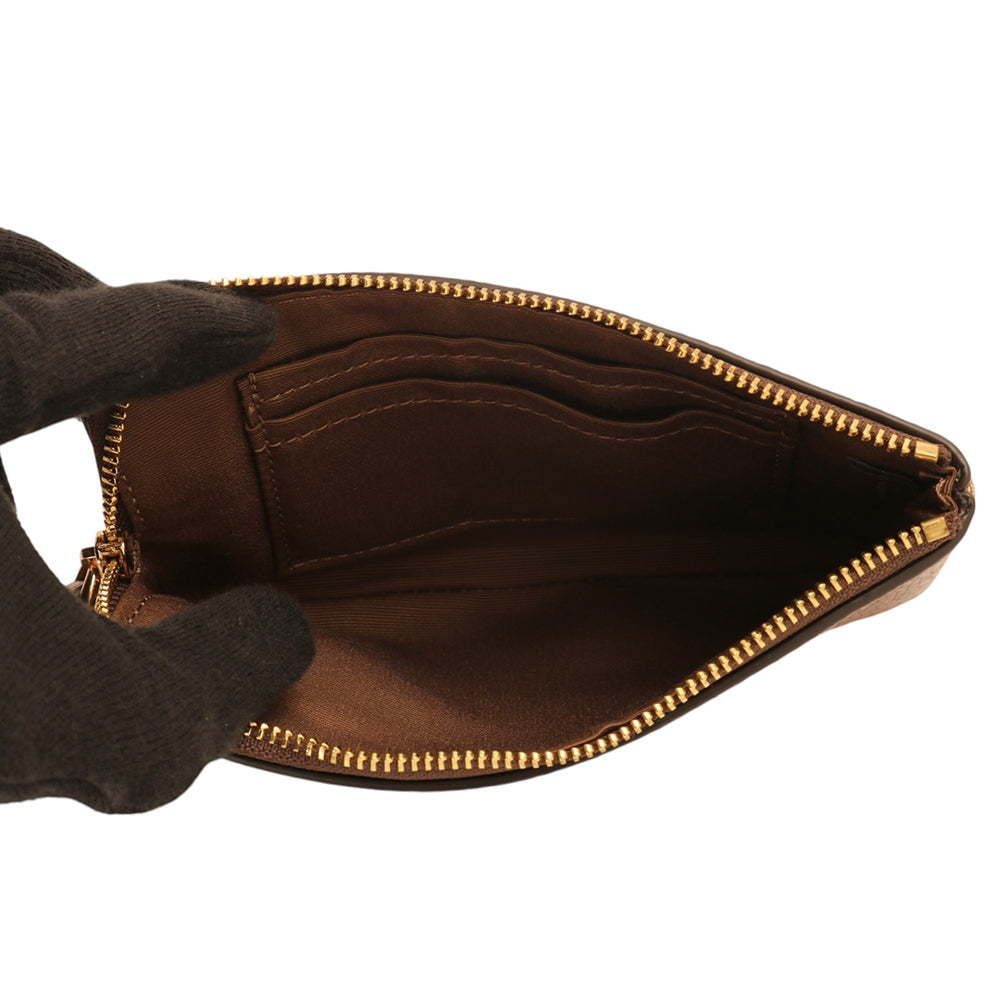 A close-up of a brown leather clutch or pouch shown open, revealing a matching brown fabric interior with card slots and gold-tone zipper hardware. A dark glove is holding the left side of the pouch against a plain white background.