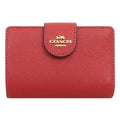 A red pebbled leather Coach wallet with a gold-tone logo on the front flap, shown against a plain white background.