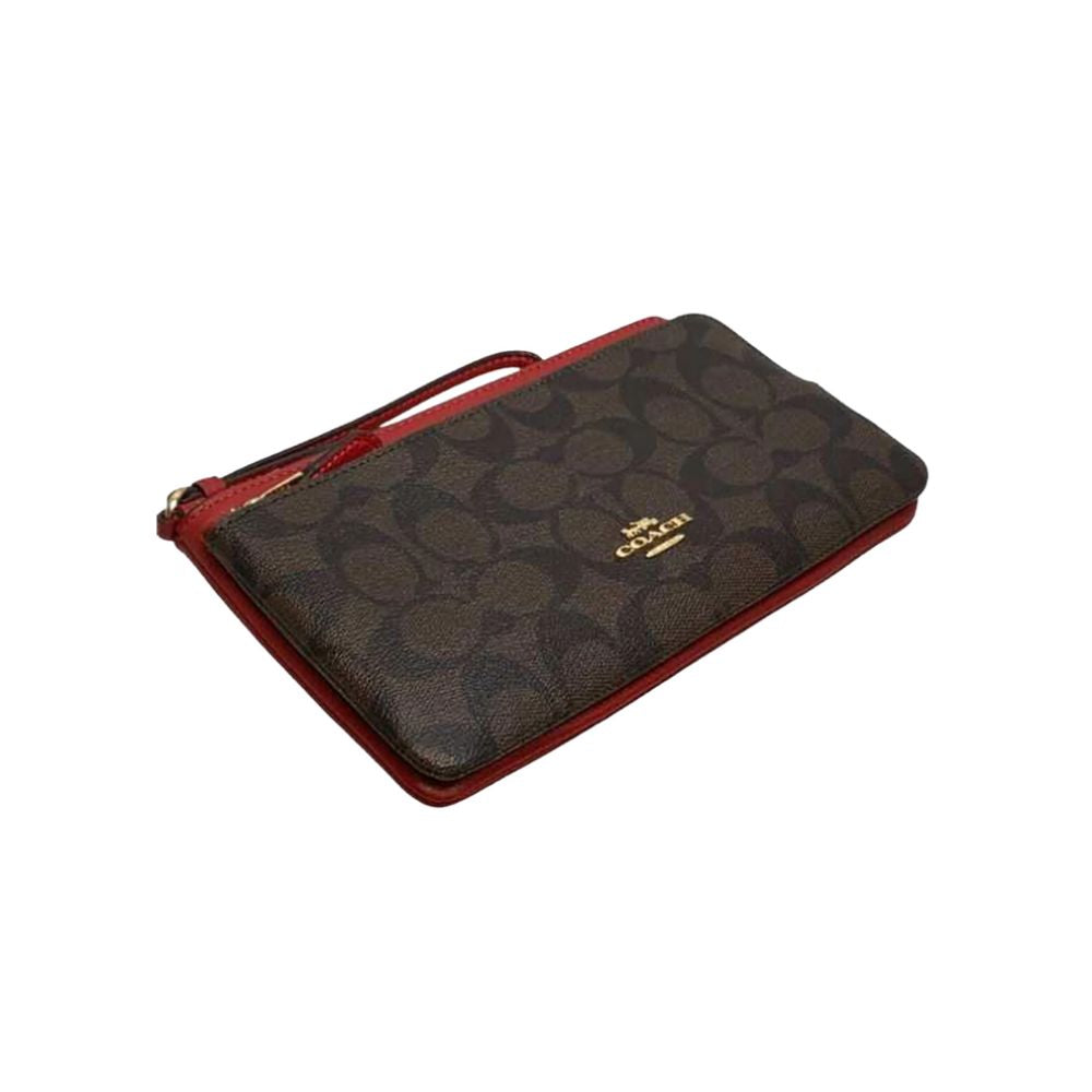 A Coach zip-around wallet in the brand's signature monogram canvas, featuring a dark brown and black pattern with red leather trim and a gold-tone logo on the front.