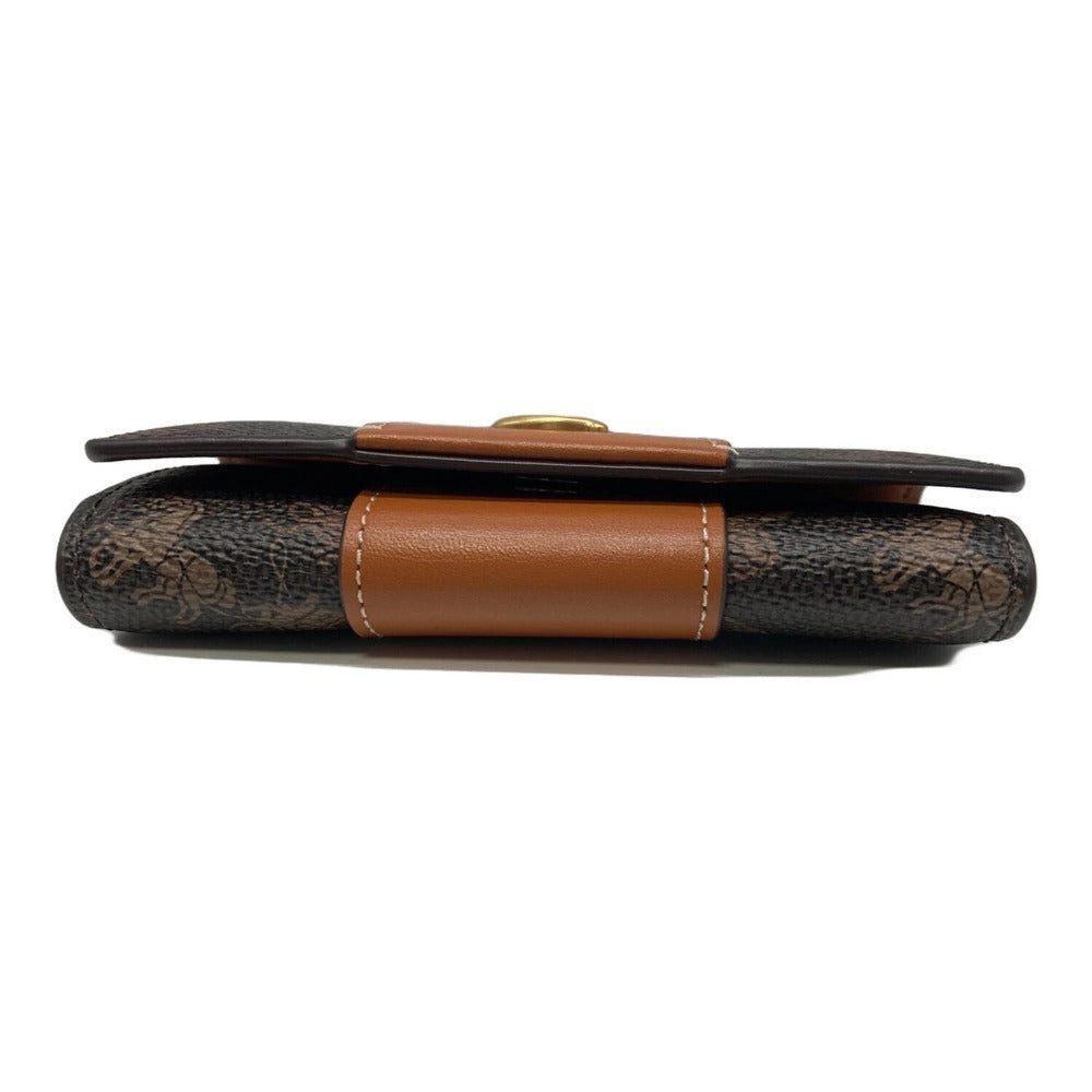 A vintage-style wallet with a dark brown and black textured pattern, accented by a smooth brown leather strap and a small gold-tone snap button.