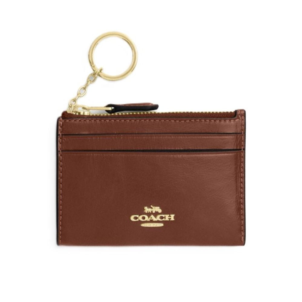 A brown leather card holder keychain with gold-tone hardware and the Coach logo on the front, shown against a plain white background.