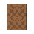 A brown and tan Coach signature pattern passport cover or notebook cover shown flat against a plain white background.