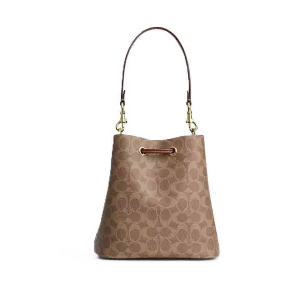 A Coach signature canvas bucket bag in brown and beige, featuring a single shoulder strap with gold-tone hardware, set against a plain white background.