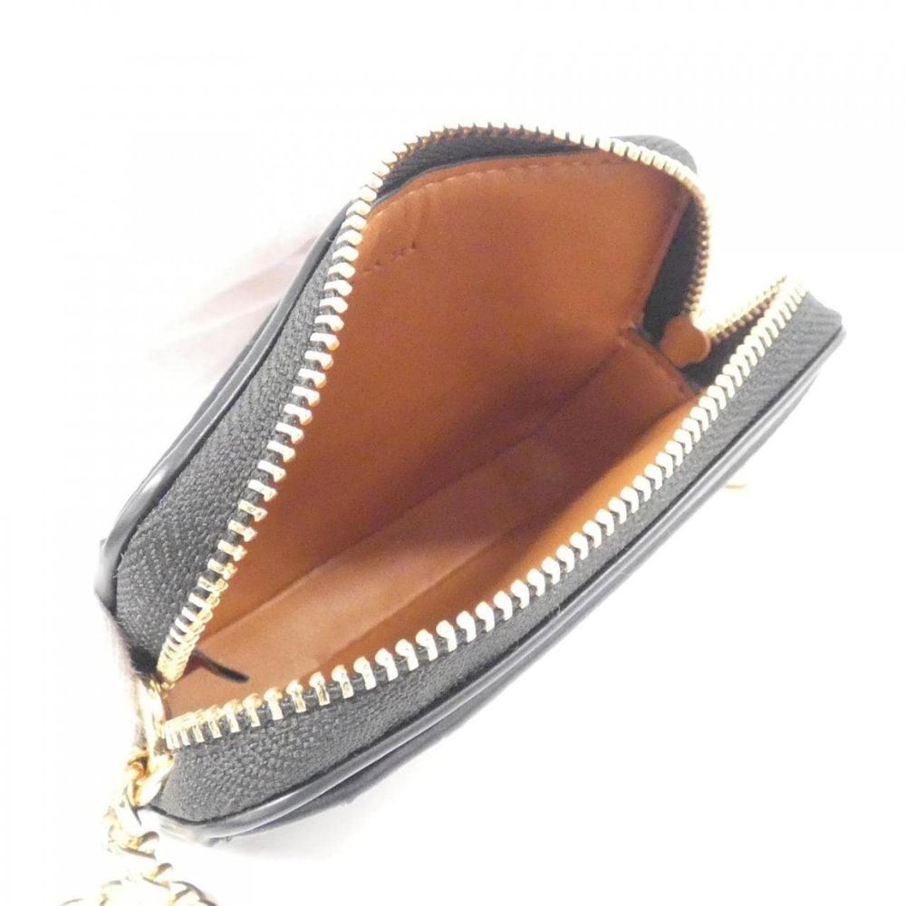 A small black textured leather coin purse with a gold-tone zipper and a tan interior lining, shown open against a white background.