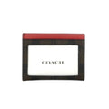 A Coach card holder featuring a dark brown and black plaid pattern with a red leather top border and a white center insert displaying the Coach logo.