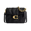 A black quilted leather Coach crossbody bag with a signature gold C logo clasp, gold chain strap, and black leather brand tag, shown on a plain white background.