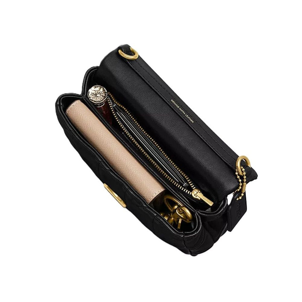 A black leather shoulder bag shown open, revealing a beige zippered pouch inside, gold-tone hardware, and a small round embellished accessory. The brand name 'MICHAEL MALCOLM' is subtly printed in gold on the black leather flap.