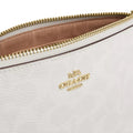 Close-up of a white textured leather pouch with a gold-tone zipper and a gold-tone Coach logo on the front.