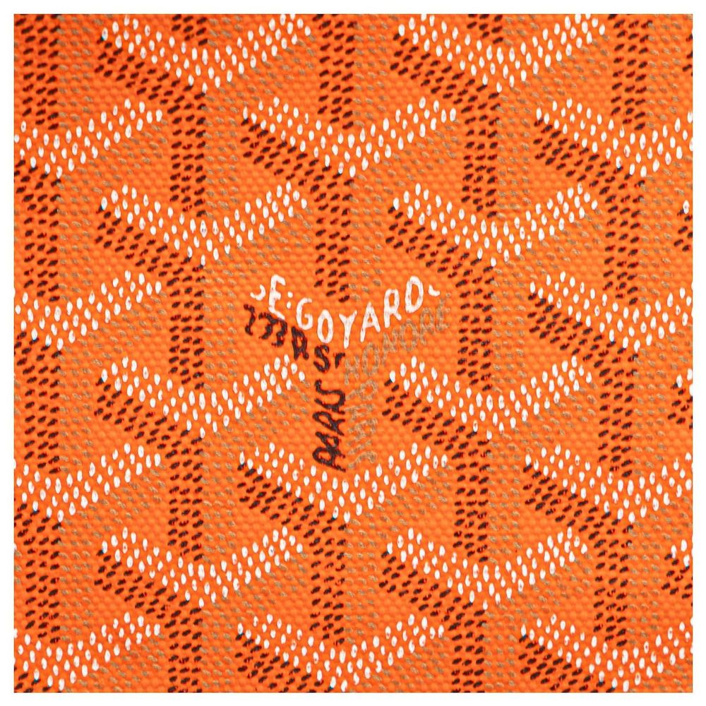 Orange Goyard canvas fabric with the brand's signature repeating chevron pattern in white and dark brown, featuring a central handwritten signature.