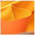 Close-up detail of a bright orange textured leather or faux-leather material with a matching orange woven fabric interior.