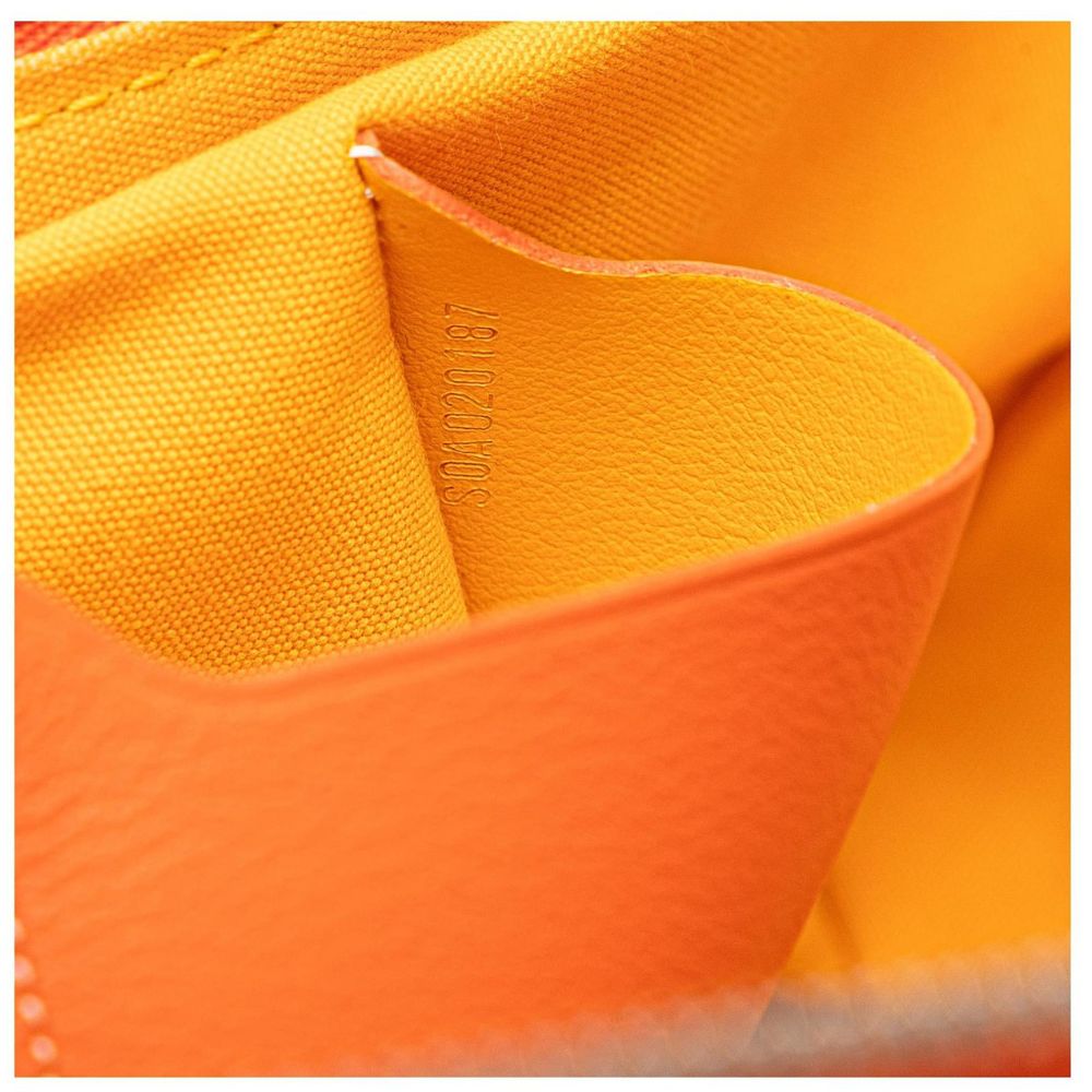 Close-up detail of a bright orange textured leather or faux-leather material with a matching orange woven fabric interior.