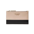 A Kate Spade New York zip-around wallet in a two-tone color-blocked design, featuring a light beige textured leather top half and a black leather bottom half, with gold-tone hardware and logo lettering.