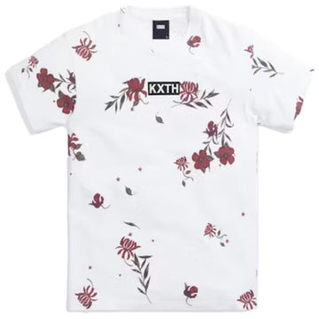 A white short-sleeve crewneck t-shirt by KXTH, featuring a scattered red and green floral print and a black rectangular logo patch on the chest with the brand name 'KXTH' in white.