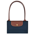 A navy blue nylon handbag with a brown textured leather flap and matching brown shoulder straps, featuring a small gold-tone circular logo button on the front.