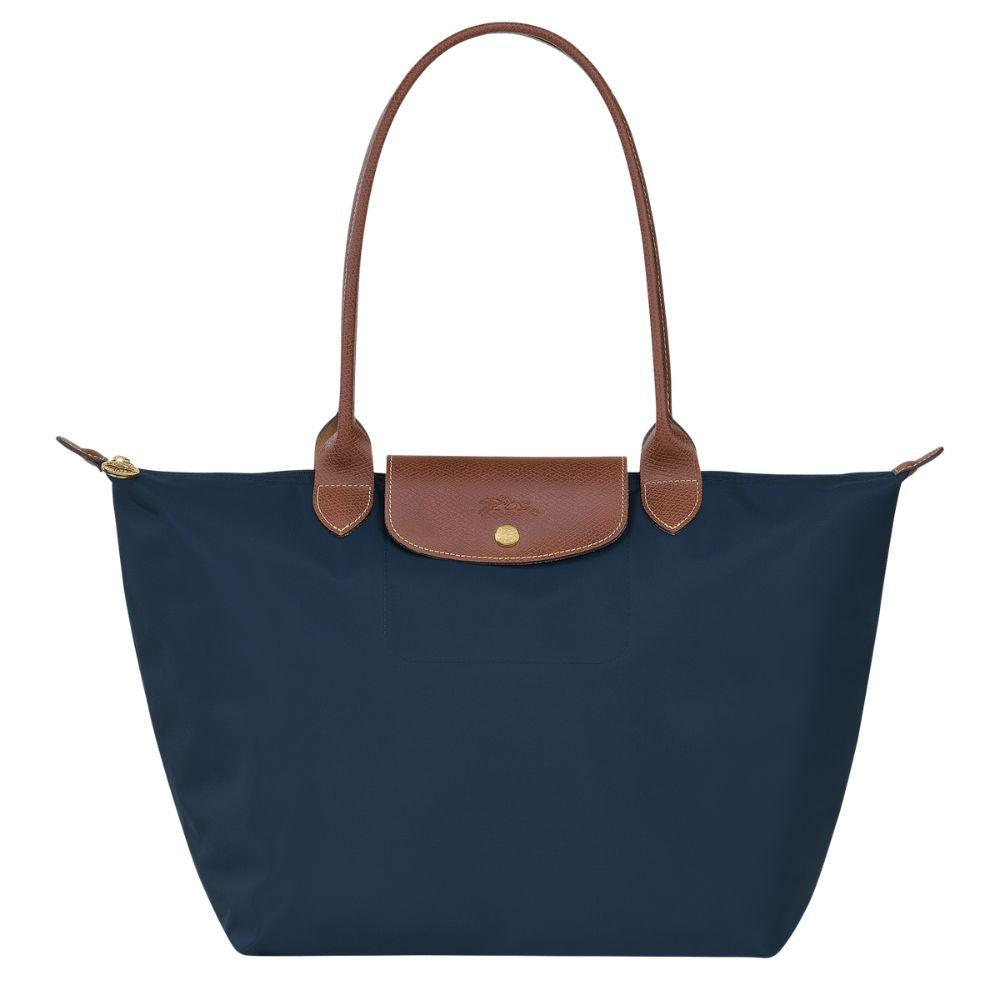 Navy blue tote bag with brown leather handle and trim on a white background