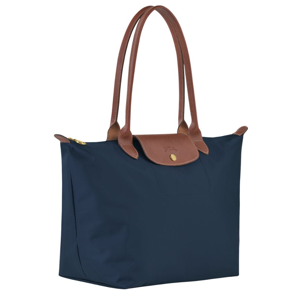 Navy blue tote bag with brown leather handles on a white background