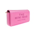 A pink pebbled leather mini bag with 'THE MINI BAG' and 'MARC JACOBS' printed in pink on the front, featuring a gold zipper pull, set against a plain white background.