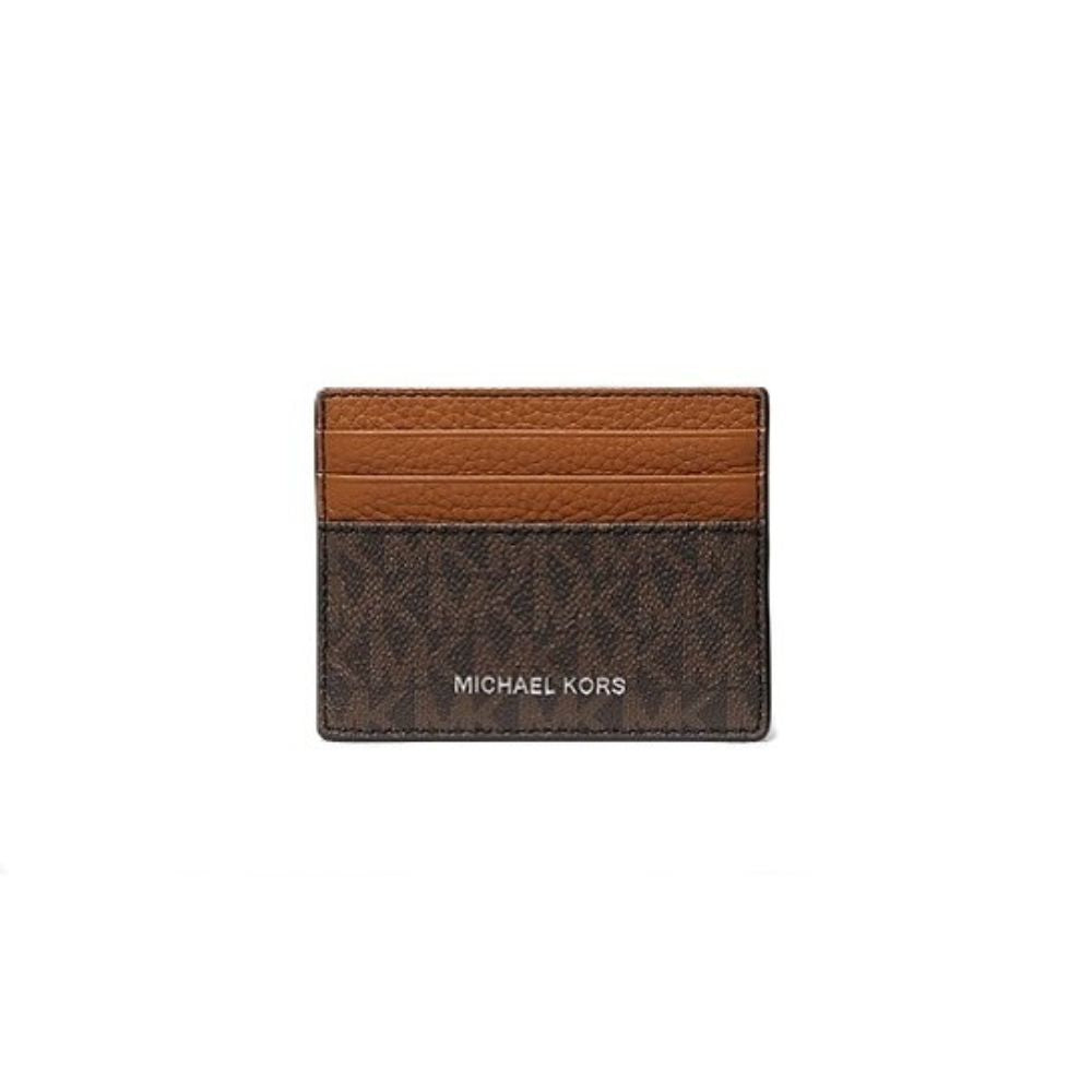 Michael Kors card holder in brown monogram canvas with a lighter brown leather stripe across the top, featuring the MICHAEL KORS logo in white on the front, set against a plain white background.