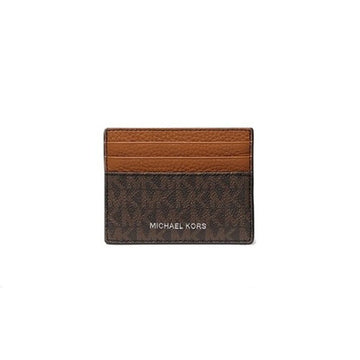 Michael Kors card holder in brown monogram canvas with a lighter brown leather stripe across the top, featuring the MICHAEL KORS logo in white on the front, set against a plain white background.