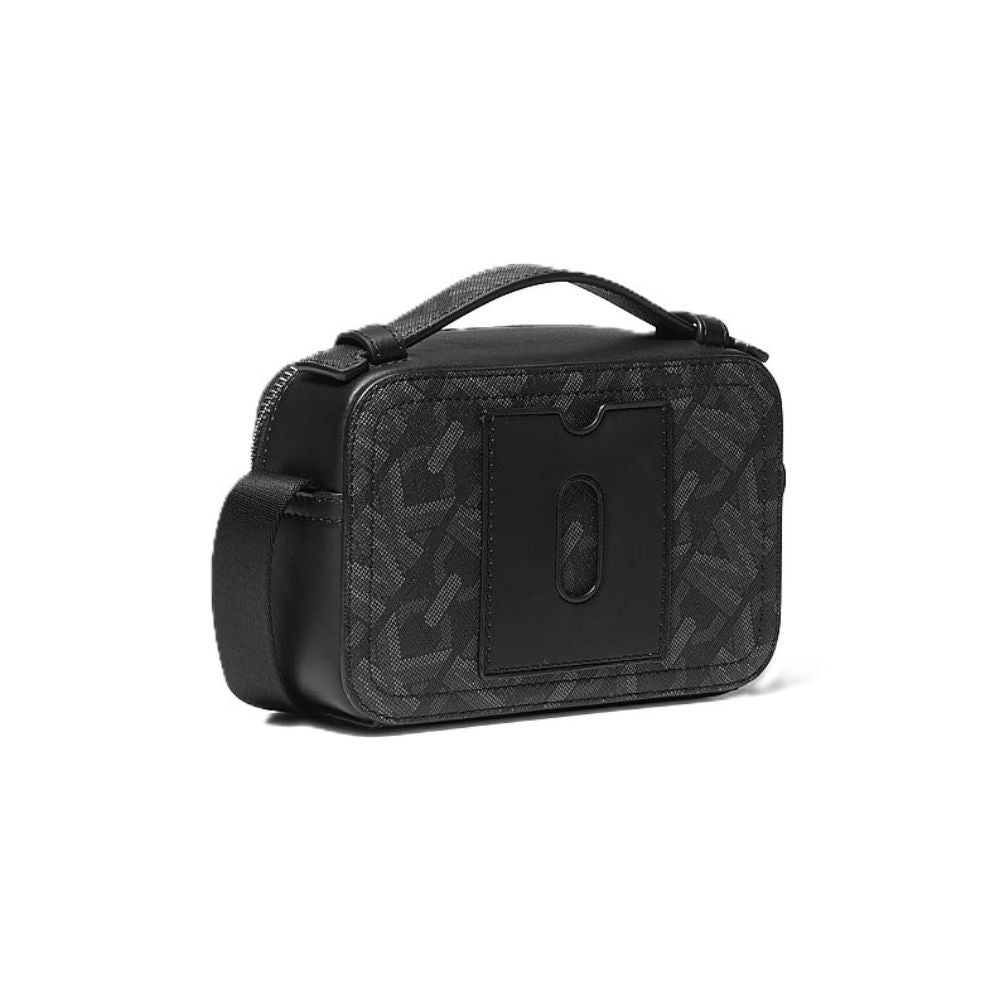 A black rectangular handbag with a top handle, featuring a dark gray and black monogram pattern on the body and a solid black front pocket with a vertical oval cutout.