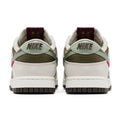 A pair of Nike Dunk Low sneakers shown from the back, featuring off-white leather overlays, olive green suede panels, a light sage green heel tab, and a dark brown outsole.