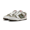 A pair of Nike Dunk Low Retro sneakers in a colorway of white, olive green, and gray, featuring a small red 'EAST END' accent on the side.