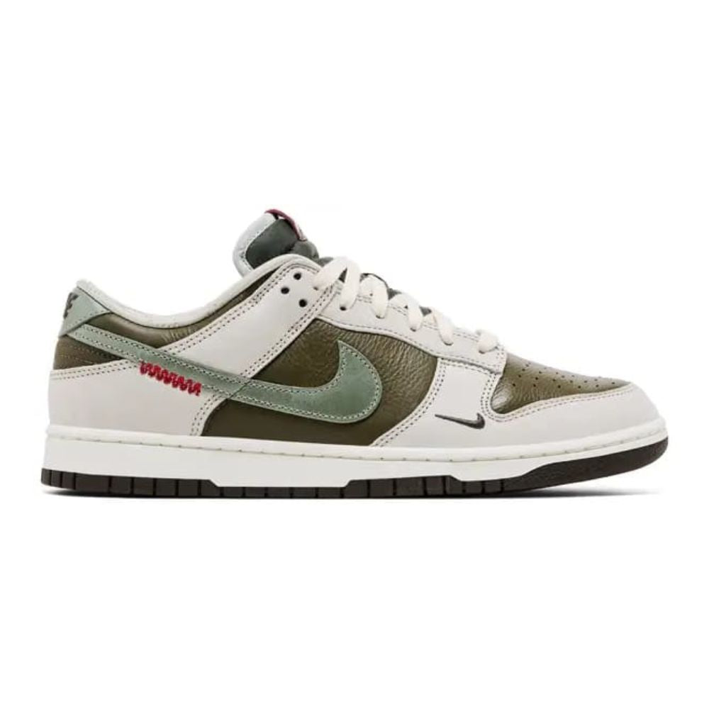 A Nike Dunk Low sneaker in off-white, olive green, and dark brown, featuring a red 'WASSHA' text detail on the side, shown against a plain white background.