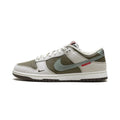 A Nike Dunk sneaker in a muted colorway featuring olive green, light gray, and white panels, with a small red 'SOURDAN' text detail on the side.