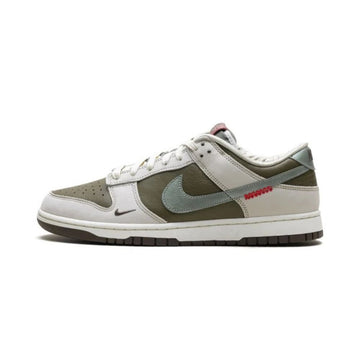 A Nike Dunk sneaker in a muted colorway featuring olive green, light gray, and white panels, with a small red 'SOURDAN' text detail on the side.