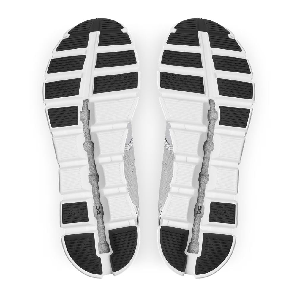 Top-down view of a pair of athletic shoes showing the outsoles, featuring a white and black tread pattern with gray midsoles on a white background.