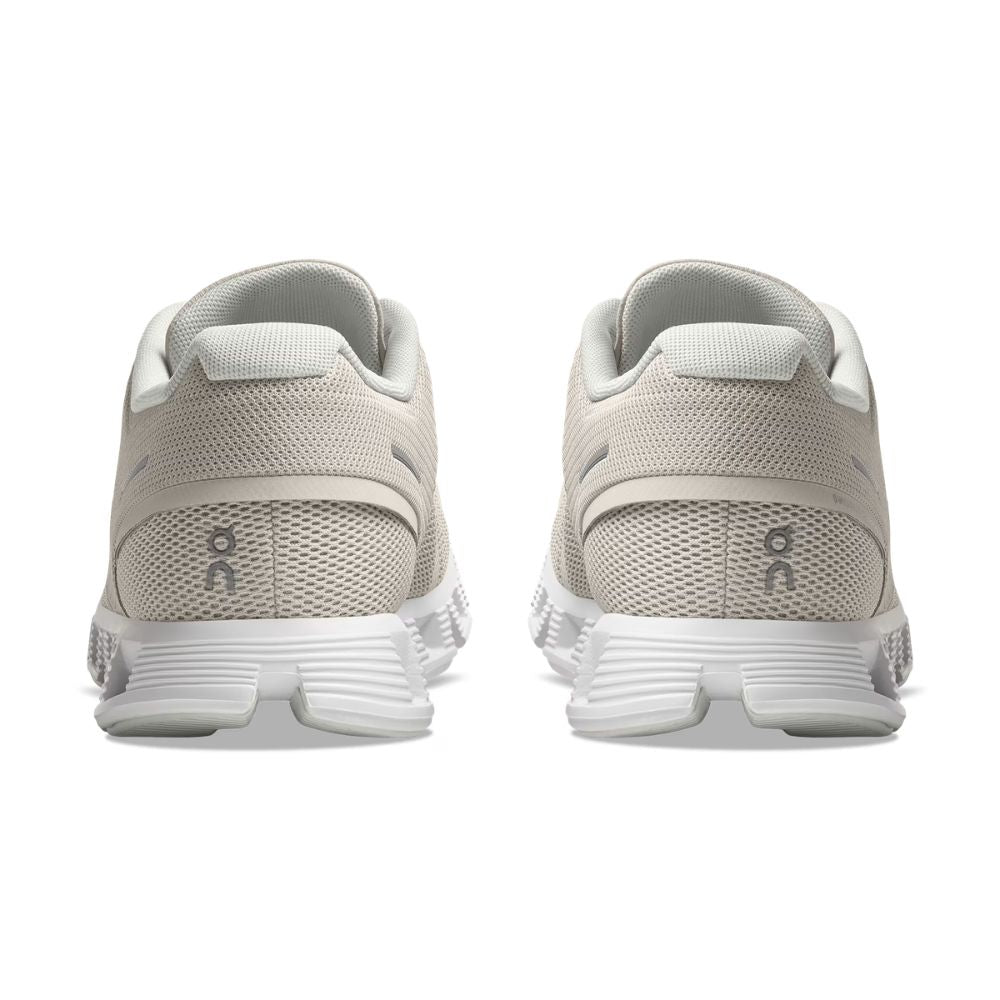 A pair of light beige running shoes shown from the back, featuring a breathable mesh upper, a thick white cushioned sole, and a small gray 'on' logo on the heel.