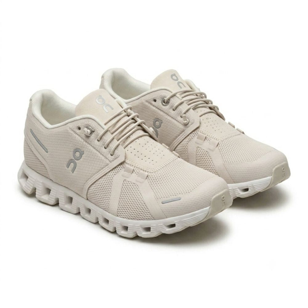 A pair of On running shoes in a light beige/off-white colorway, featuring a breathable mesh upper, matching laces, and a chunky sculpted sole, shown against a plain white background.
