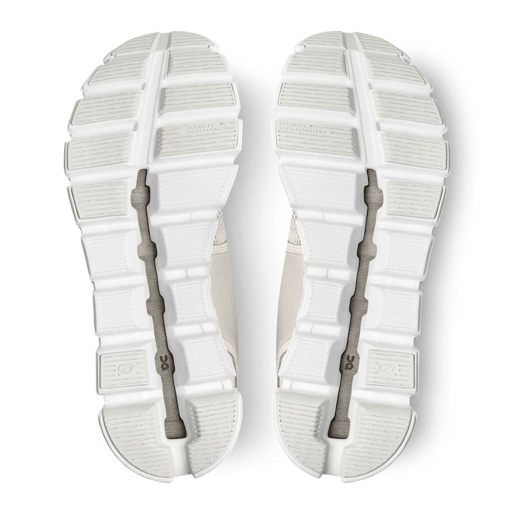 Top-down view of a pair of white athletic shoes showing the textured outsoles and gray elastic laces.