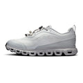 A light gray and white low-top athletic sneaker shown from the side profile on a clean white background. The shoe features a textured mesh upper, a chunky sculpted sole with circular cutouts, and a small embossed logo on the side.