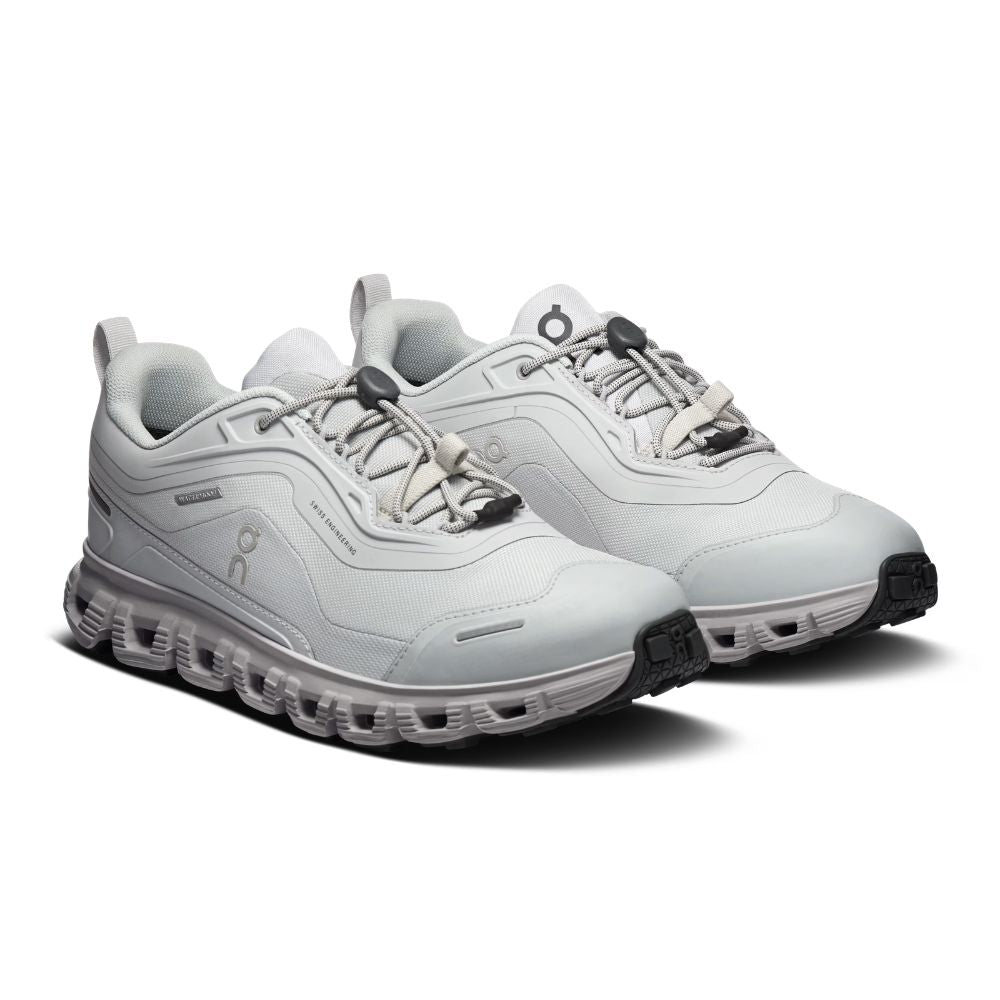 A light gray and white low-top athletic sneaker shown from the side profile on a clean white background. The shoe features a textured mesh upper, a chunky sculpted sole with circular cutouts, and a small embossed logo on the side.