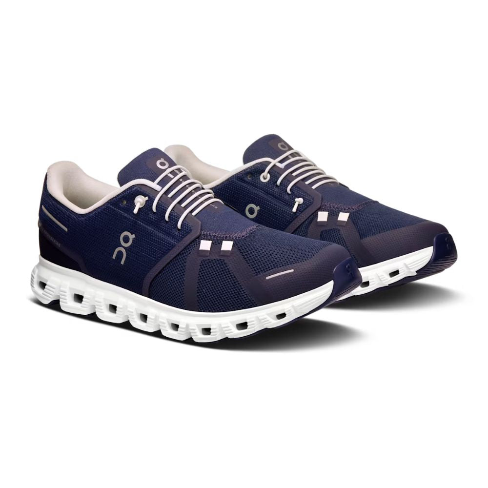 Pair of navy running shoes with white soles on a white background