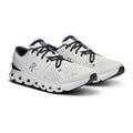 A pair of On running shoes in white and black, featuring a breathable mesh upper, black laces, and a distinctive wavy white and black sole, shown against a plain white background.