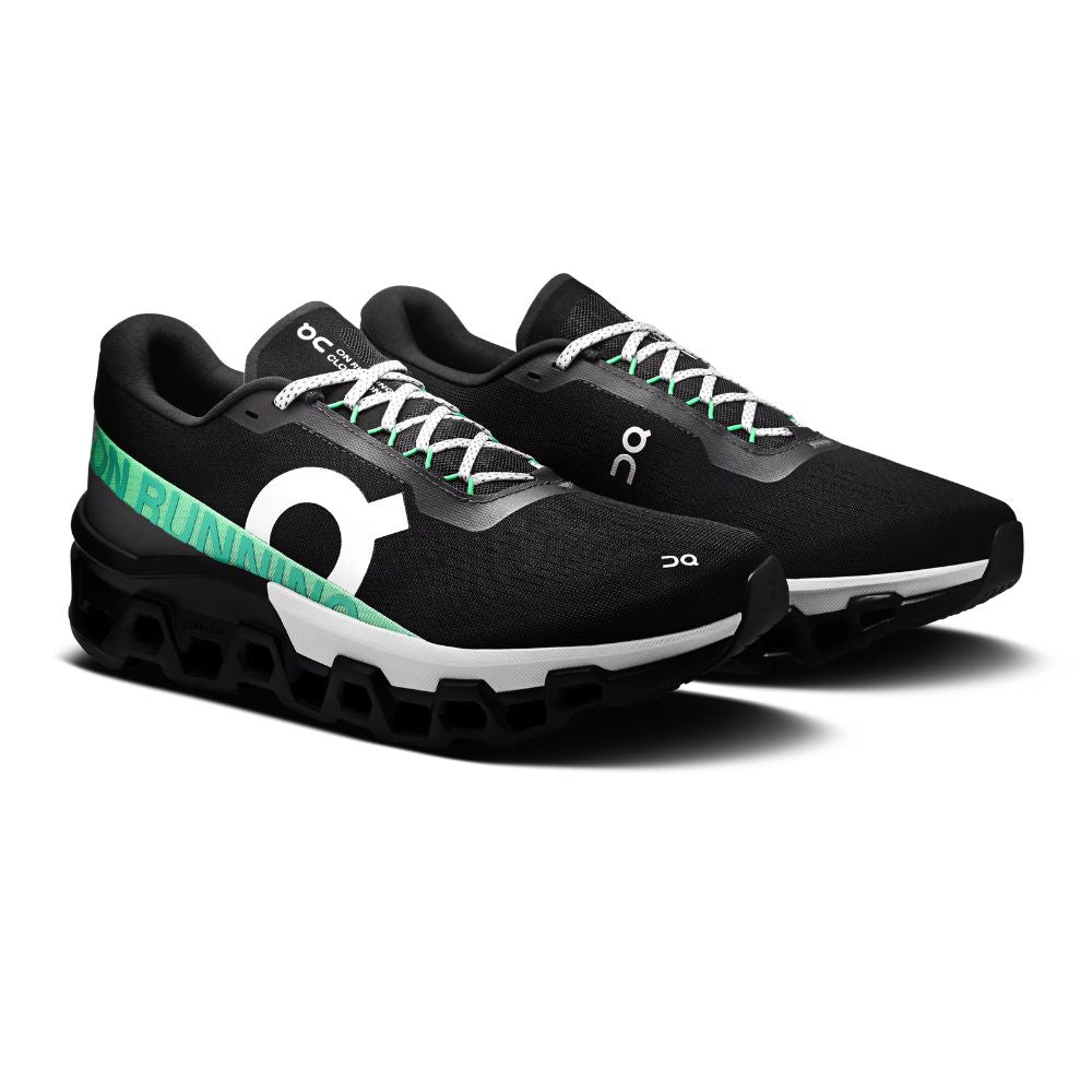 A pair of black On Cloudrunning shoes with a distinctive green and white side stripe, white laces, and a white midsole, shown on a clean white background.