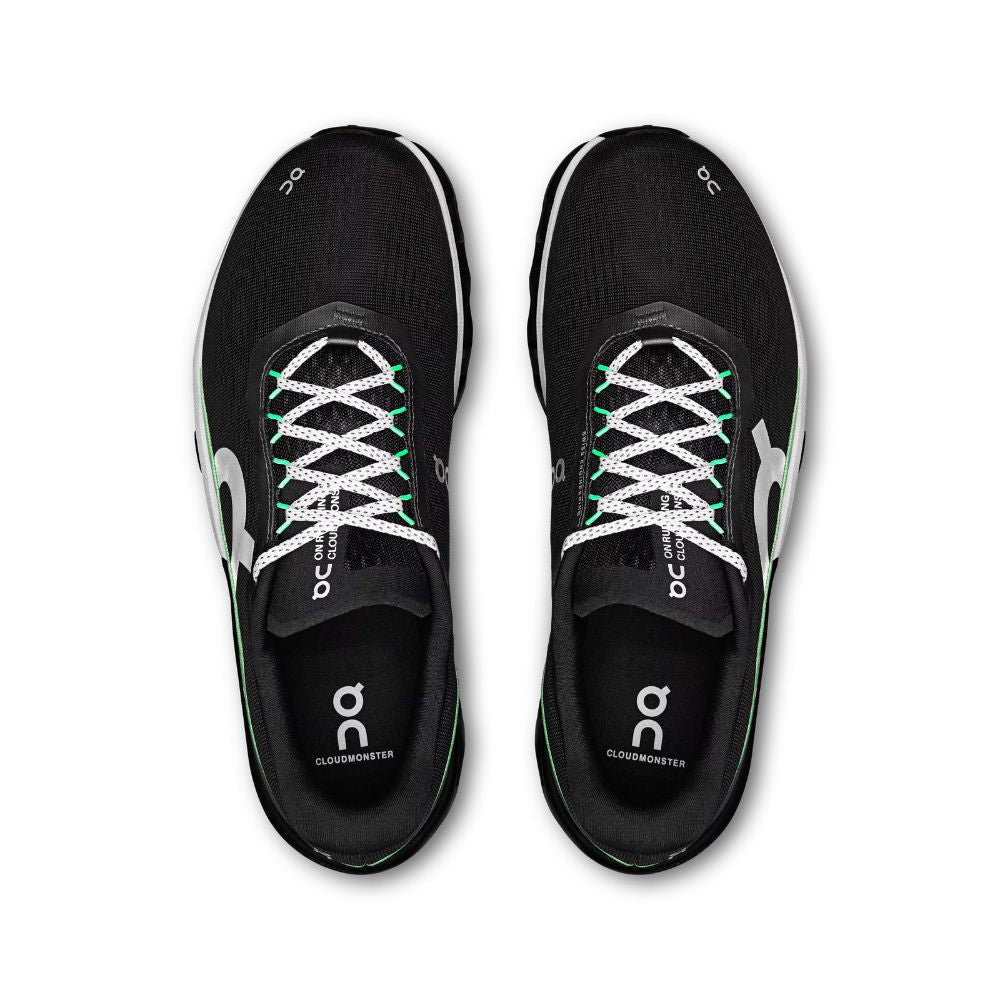 A pair of black On running shoes with white laces and green accents, shown from a top-down view on a white background.