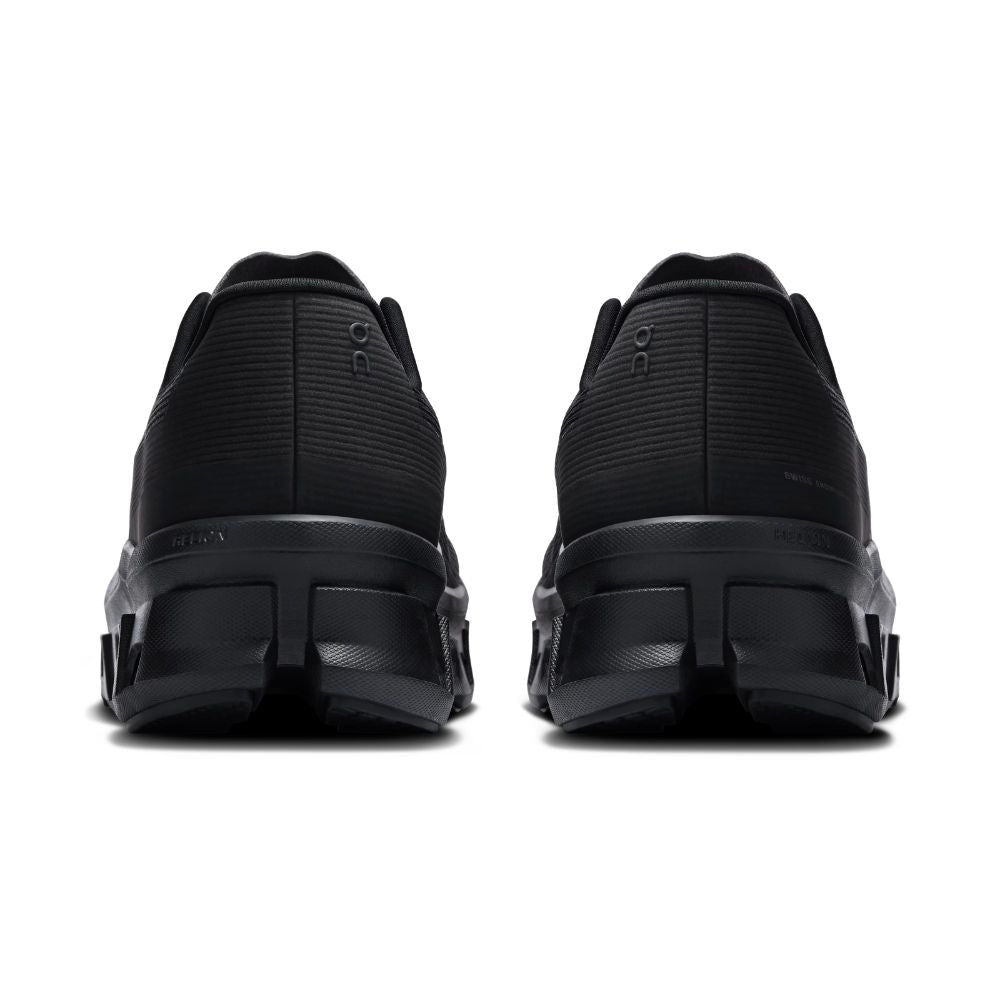 A pair of black athletic sneakers shown from the rear, featuring textured upper panels and chunky black soles, set against a plain white background.