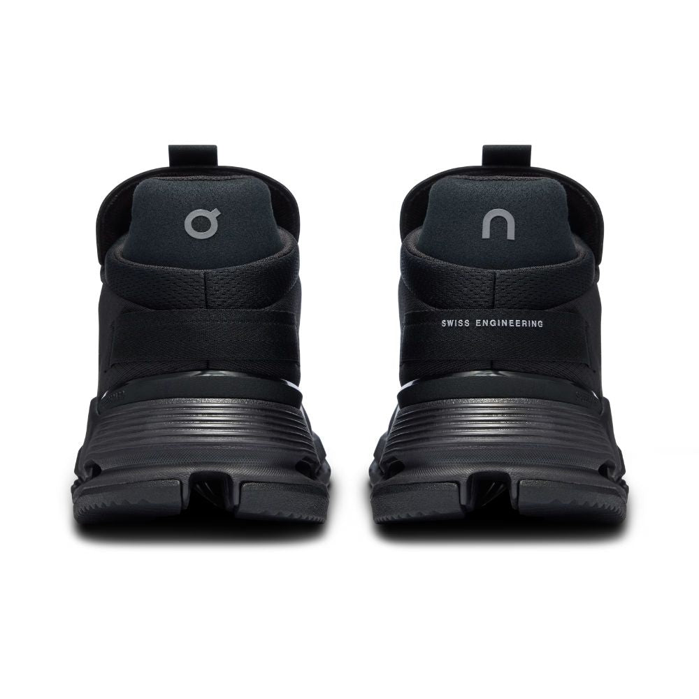 A pair of black high-top athletic sneakers shown from the back, featuring a textured synthetic upper, thick ridged black midsoles, and a pull tab on the heel, set against a plain white background.