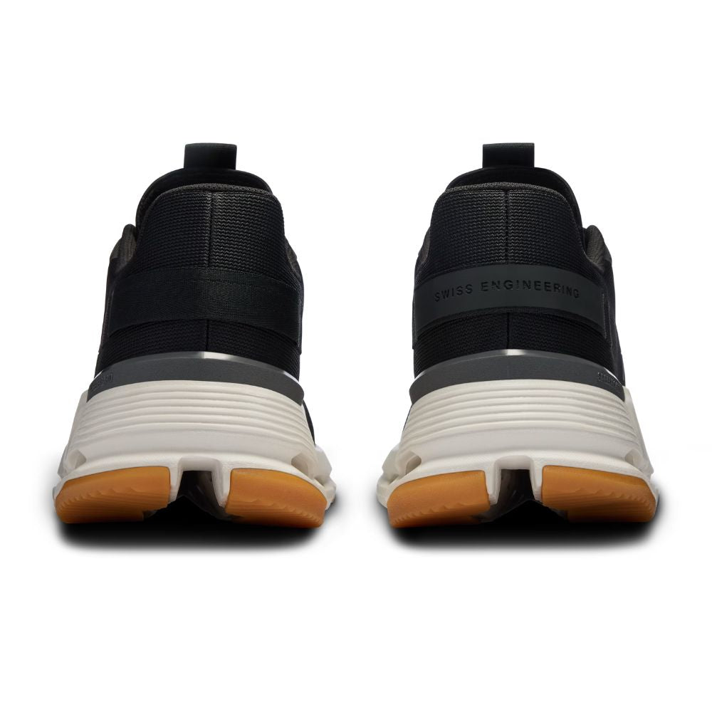 A pair of black athletic sneakers shown from the rear, featuring a thick white midsole with gum rubber outsoles and 'SWISS ENGINEERING' printed on the heel.