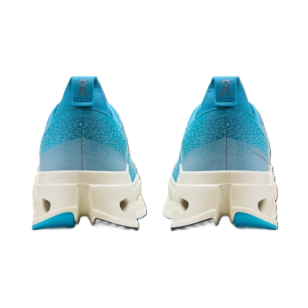 A pair of athletic sneakers shown from the back, featuring a bright blue and teal knit upper, a translucent light blue heel section, and a chunky off-white midsole with a small blue accent at the outsole.