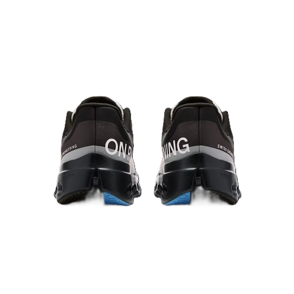 A pair of black and gray running shoes shown from the back, featuring white 'ON' and 'NING' lettering on the heel area and a small blue accent at the sole.